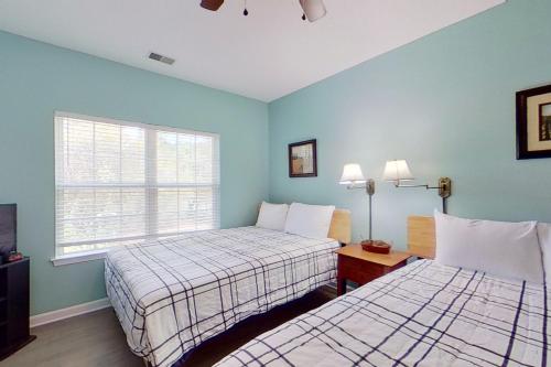 Duas camas num quarto com paredes azuis e uma janela em Homey Beach Hideaway em Myrtle Beach