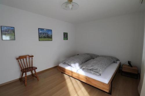 a bedroom with a bed and a chair in it at Siesta 3,5-Zimmer-Wohnung in Leukerbad