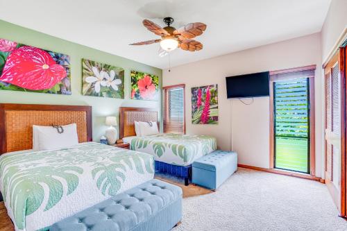 a bedroom with two beds and a ceiling fan at The Golden Hibiscus - Lanikai 222 in Kapaa