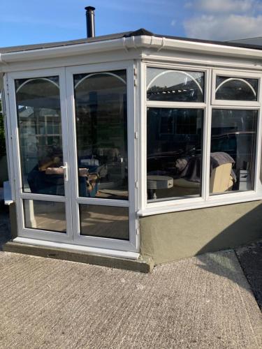 a conservatory with windows on the side of a house at Junes cosy apartment in Mayo