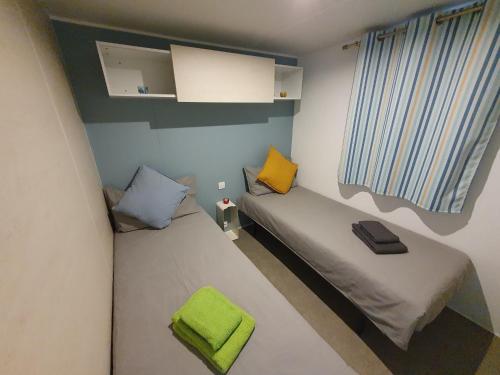 een kleine slaapkamer met 2 bedden en een groen kussen bij Campingland Ostsee - Mobilheim 157Sandburg in Schashagen
