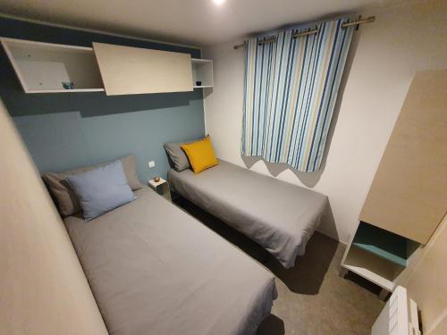 mały pokój z 2 łóżkami i oknem w obiekcie Campingland Ostsee - Mobilheim A2Meeresbriese w mieście Schashagen