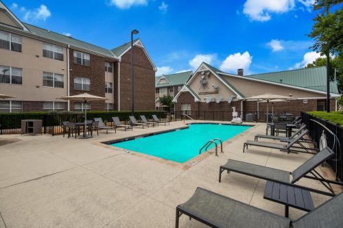 a swimming pool with tables and chairs next to a building at Sonesta ES Suites Dallas Richardson in Richardson