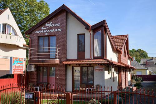 a brown and white house with a red fence at SovaApartman in Hajdúszoboszló