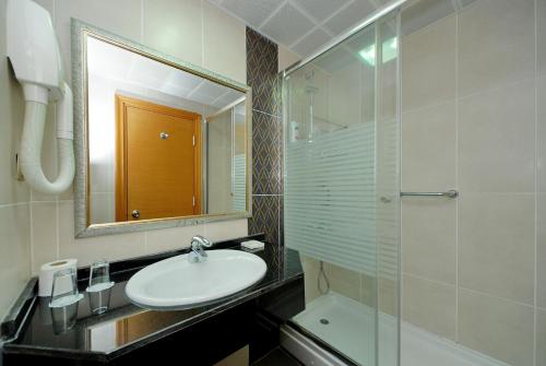 a bathroom with a sink and a mirror and a shower at Pasabey Hotel in Marmaris