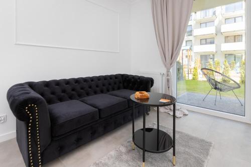 a black couch in a living room with a table at Gdynia Nasypowa Apartments with Parking by Renters in Gdynia