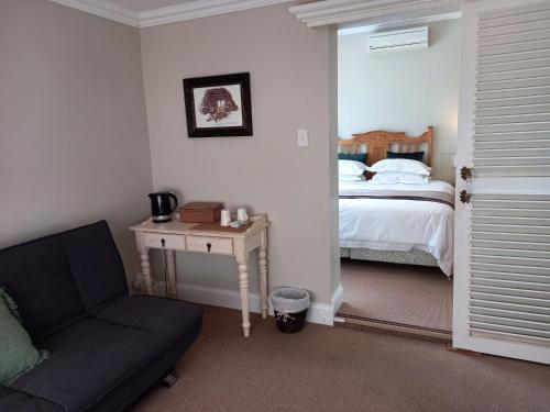 a bedroom with a bed and a couch and a table at La Pension Guest House in Oudtshoorn