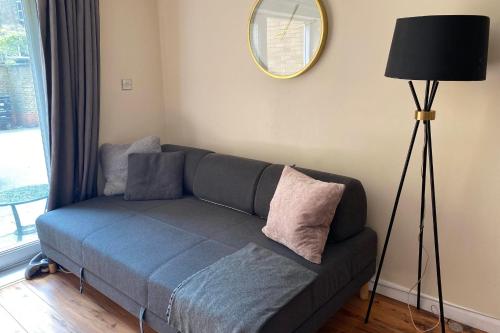 1 sofá en la sala de estar con espejo y lámpara en Stylish and Homely 4 Bedroom Home in East London en Londres