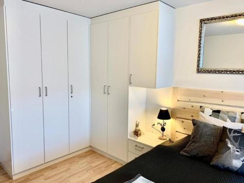 - une chambre avec des placards blancs, un lit et un miroir dans l'établissement Ferienwohnung Bolgen - bei Jakobshorn Bahn, Skischule, Bushaltestelle, Supermarkt, Restaurants, à Davos