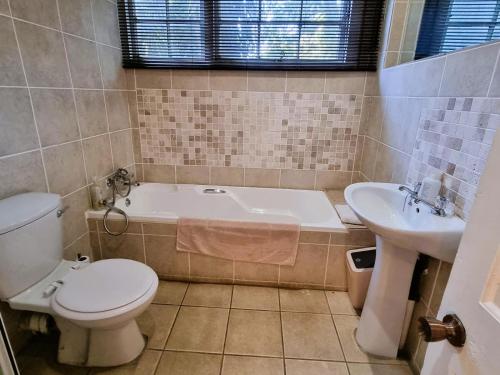 a bathroom with a tub and a toilet and a sink at Bonnie Highlands in Ladysmith