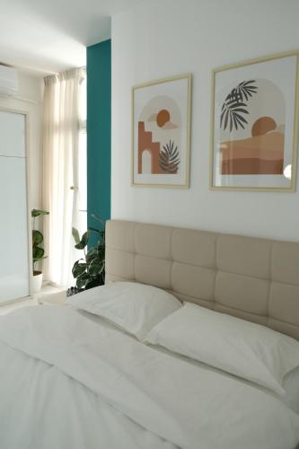 ein Schlafzimmer mit einem weißen Bett mit zwei Bildern an der Wand in der Unterkunft Modern Apartment at Train Station in Tirana