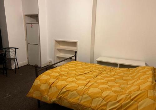 Wembley Park Studios في لندن: غرفة نوم بسرير اصفر وثلاجة