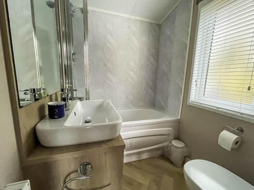 y baño con lavabo, bañera y aseo. en Beautiful Lodge With Decking At Azure Seas In Suffolk, Sleeps 6 Ref 32217og en Lowestoft