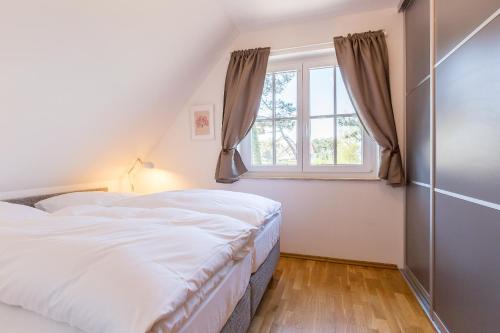 a bedroom with a white bed and a window at Strandleben 10 - Louis Douzette in Ahrenshoop