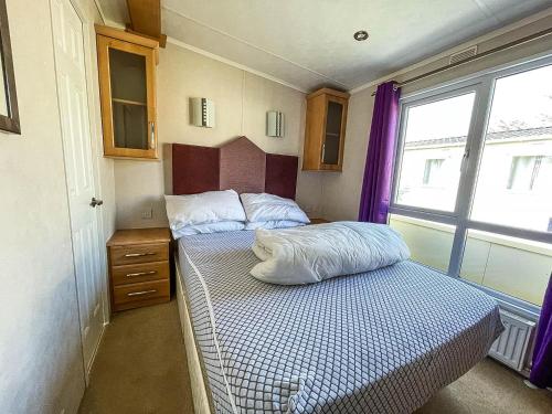 a small bedroom with a bed and a window at 6 Berth Caravan With Decking At Cherry Tree Park In Norfolk Ref 70014g in Great Yarmouth