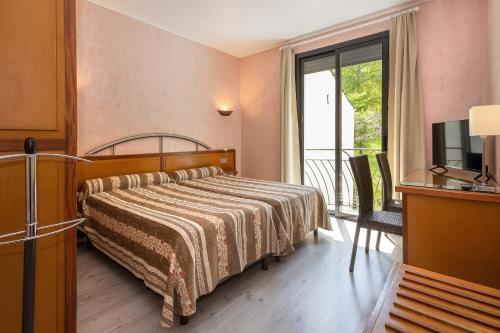 a hotel room with a bed and a balcony at Logis Hôtel Restaurant Le Mont Aigoual in Meyrueis