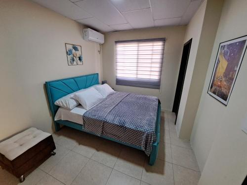 niewielka sypialnia z niebieskim łóżkiem i oknem w obiekcie Casa Vacacional en Conjunto Privado w mieście Manta