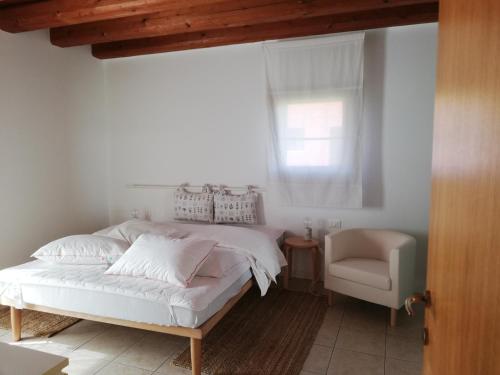 a bedroom with a bed and a chair and a window at Corte Monticello in Barbarano Vicentino