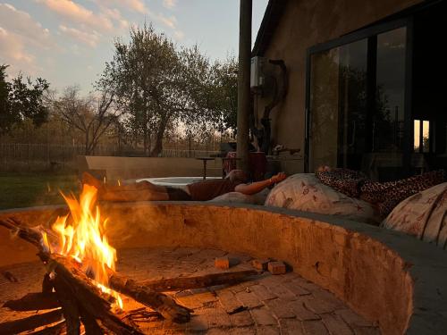 Una hoguera con dos personas sobre almohadas alrededor en Simba Safaris African Pride Exotic Lodge en Lephalale