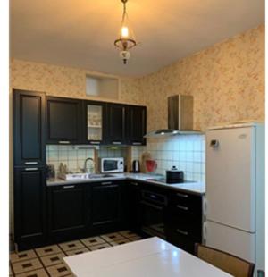 - une cuisine avec des armoires noires et un réfrigérateur blanc dans l'établissement La Miséricorde, à Coutances