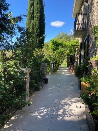 a long sidewalk with trees and a building at El Cau de Cal Quimet in Rialp