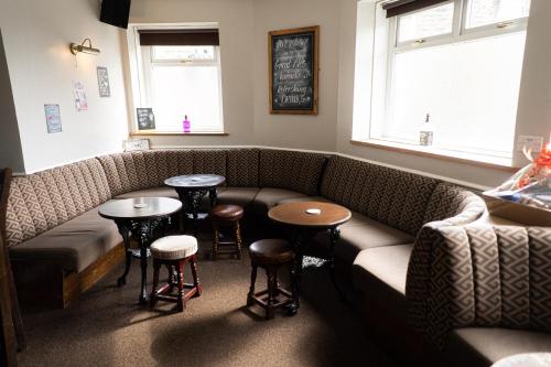 a bar with a couch and two tables and stools at Masons Arms Amble in Amble