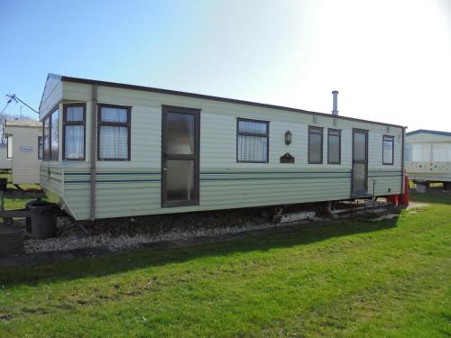a green trailer sitting in a grass field at 8 Berth panel heated on Coral Beach (Willerby Westmorland) in Ingoldmells