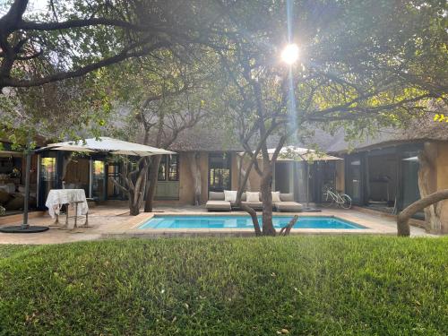 una piscina con sombrilla junto a una casa en Simba Safaris African Pride Exotic Lodge en Lephalale