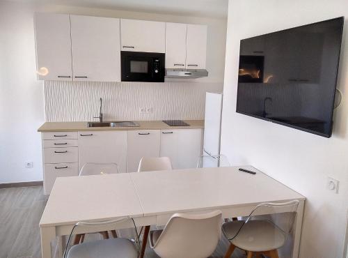 biała kuchnia z białym stołem i krzesłami w obiekcie Résidence Graziella Appartement 510 w mieście Juan-les-Pins