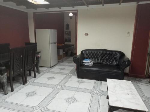 uma sala de estar com um sofá preto e uma cozinha em Manial El roda no Cairo