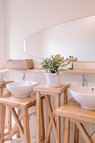 a bathroom with three white sinks on wooden tables at Happiness Hostel Siargao in General Luna