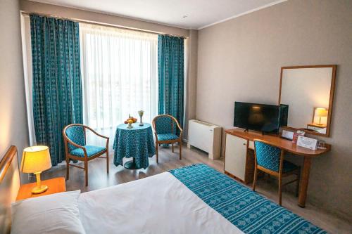 a hotel room with a bed and a table with chairs at Hotel Trotuş in Onești