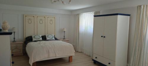 a white bedroom with a bed and a dresser at Apartament WILLA ANTA in Dębno