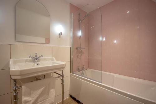 La salle de bains est pourvue d'un lavabo et d'une douche. dans l'établissement Breckland Thatched Cottage, à Hockwold cum Wilton