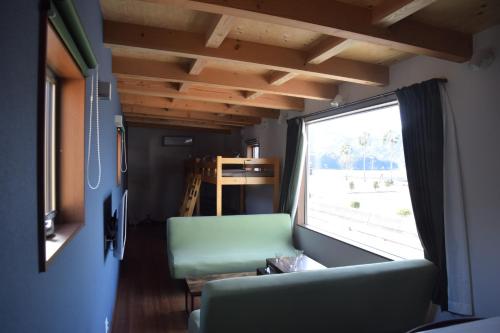 ein Wohnzimmer mit einem grünen Sofa und einem Fenster in der Unterkunft 伯方plus+ in Imabari