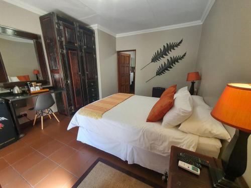 Micasa Sucasa Guesthouse في Lephalale: غرفة نوم مع سرير ومكتب مع مصباح