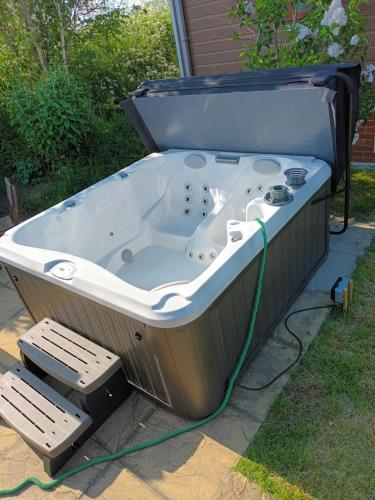 a jacuzzi tub sitting in a yard with two chairs at Fern Lodge with Hot Tub in Stonham Aspall
