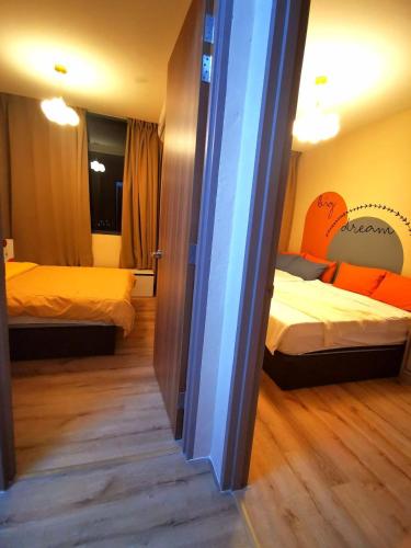 a bedroom with two beds with orange sheets and a mirror at Stylish Micasa 4 Home 3BR+FREE PARKING -Hann's Residence in Sibu