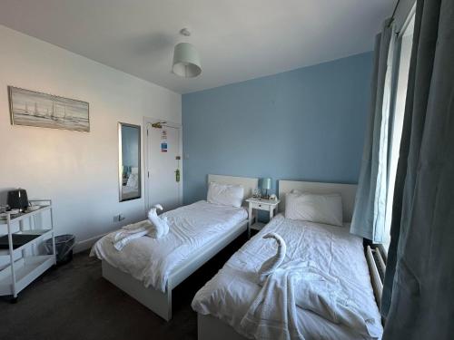 two beds in a room with blue walls at Masons Arms Amble in Amble