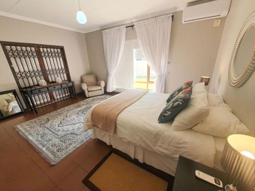 a bedroom with a bed and a chair and a window at Micasa Sucasa Guesthouse in Lephalale