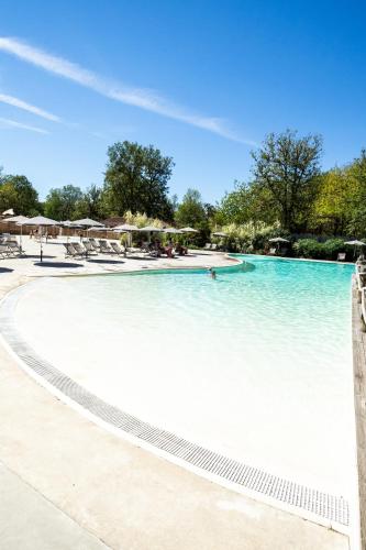 a swimming pool with blue water in a resort at Huttopia Lac de l'Uby - Gers in Cazaubon