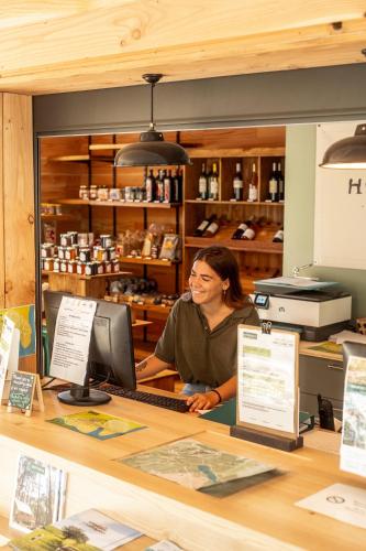 a woman sitting at a counter in a store at Huttopia Lac de l'Uby - Gers in Cazaubon