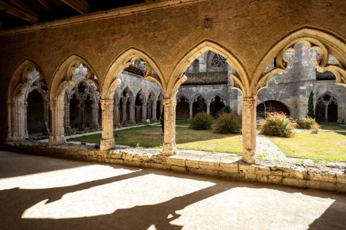 a building with arches and a shadow on the ground at Huttopia Lac de l'Uby - Gers in Cazaubon