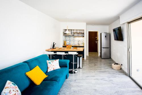ein Wohnzimmer mit einer blauen Couch und einer Küche in der Unterkunft Romantic sea view studio, steps away from the beach in Antibes