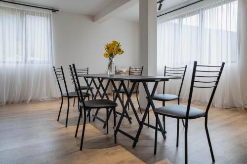 a black dining room table with chairs and a vase of flowers at "Panorama" Kakhri in Mestia