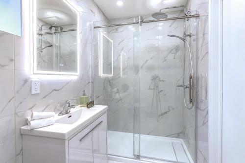 uma casa de banho branca com um chuveiro e um lavatório. em Cozy oasis double king size bed: Bell Center - Heart of downtown em Montreal