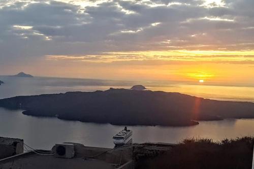 a boat in a body of water at sunset at Pleasure Black Beach Perissa Santorini in Perissa