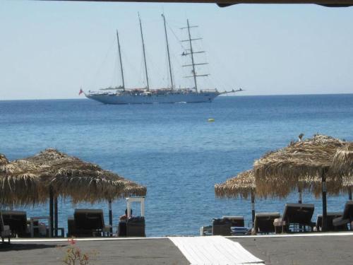 a ship in the ocean with chairs and straw umbrellas at Pleasure Black Beach Perissa Santorini in Perissa