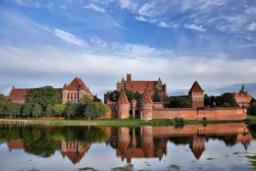 a castle with its reflection in a body of water at Apartament Queen in Malbork
