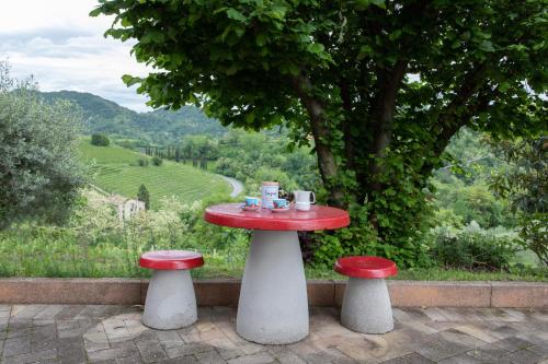 a table with two stools and a red and white table with a view at La collina dei nonni - Tarzo in Tarzo